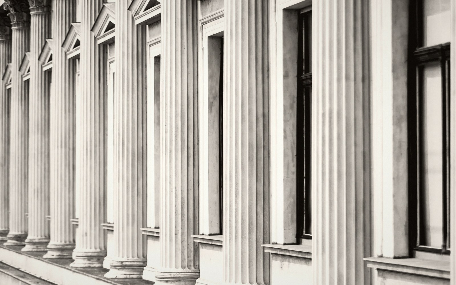 The stone facade of a Ringstraße institution in raking afternoon light, columns casting long shadows